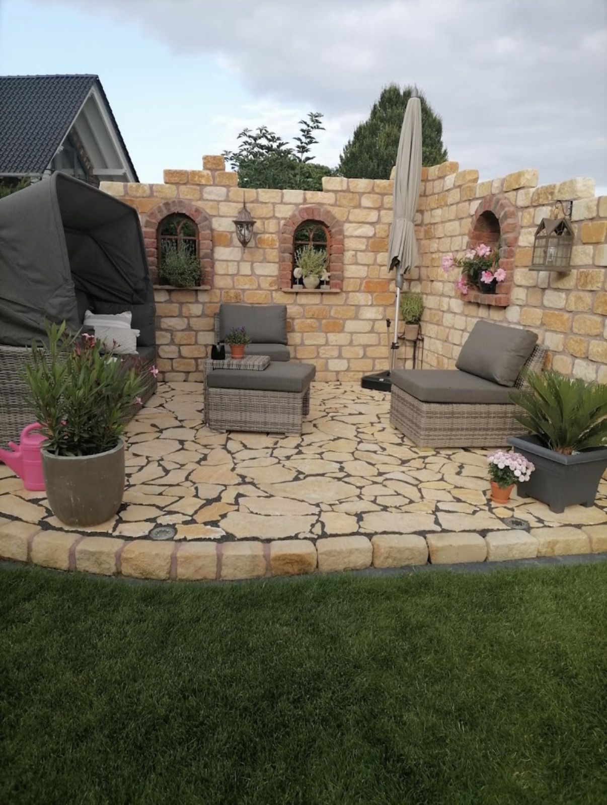 Sitzplatz vor einer Natursteinmauer im Ruinenstil mit Polygonal-Terrasse