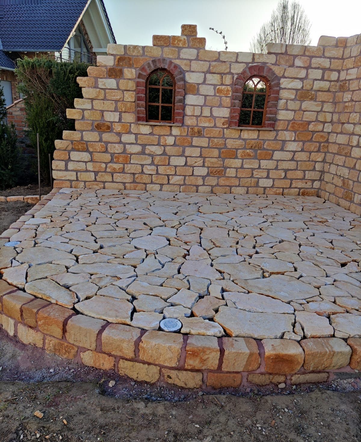 Polygonalplatten frisch verlegt vor der Natursteinmauer